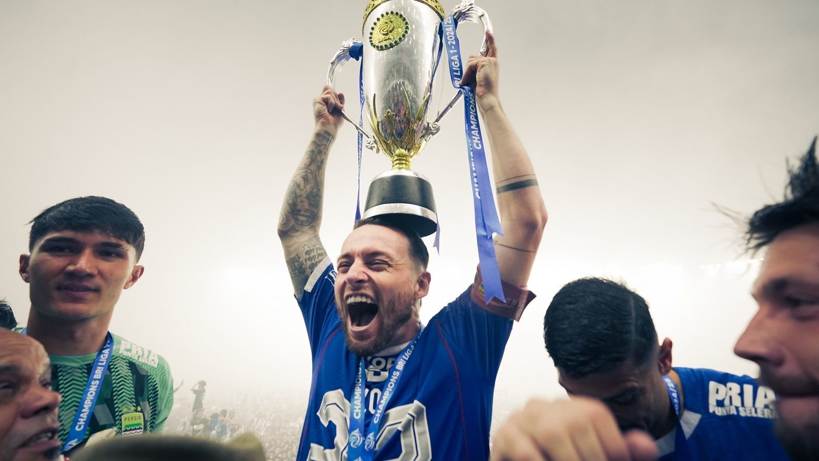 Marc Klok merayakan keberhasilan Persib Bandung menjuarai Liga 1 2024-2025 dengan meletakan trofi di atas kepalanya di Stadion Gelora Bandung Lautan Api (GBLA), Bandung, 24 Mei 2025. (Yogie Gandanaya/Skor.id)
